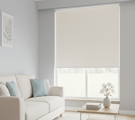 Cream roller blind covering a window in a bright, minimalist living room.