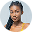 Young Black woman with braids looking at camera, wearing a yellow top.