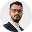 Man with beard and glasses smiling in a circular profile picture.