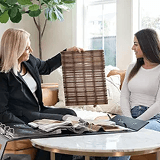 Interior designer showing wood blind sample to client for home decor discussion.